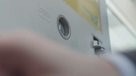 hand of business person depositing coins into an atm in frankfurt, germany