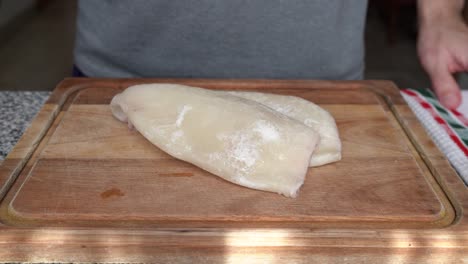 Man-Places-Skinless-Squid-On-Wooden-Board-In-The-Kitchen