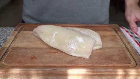 el hombre coloca el calamar sin piel en una tabla de madera en la cocina