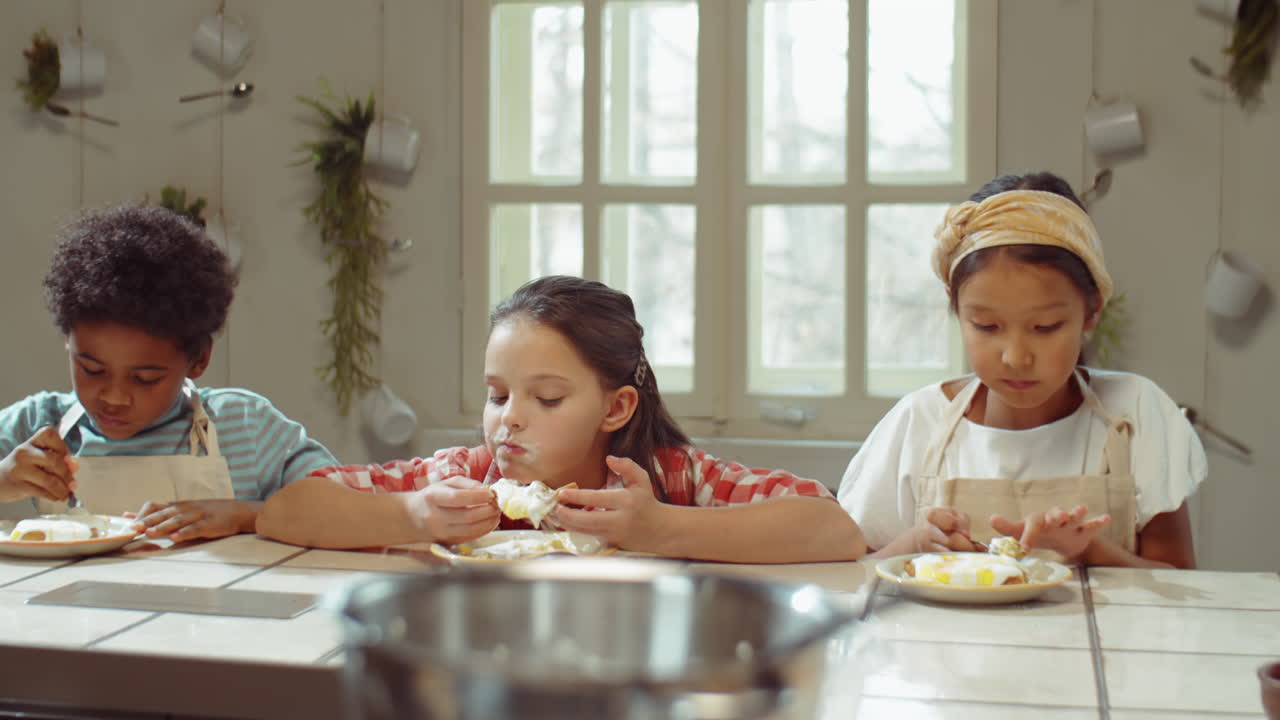 Bambini multietnici che mangiano waffle dolci durante una lezione di cucina