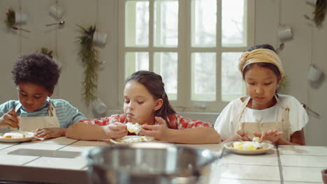 multiethnic kids eating sweet waffles on culinary lesson