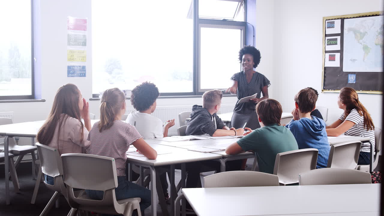 Female High School Tutor Standing By Table With Students Teaching Lesson