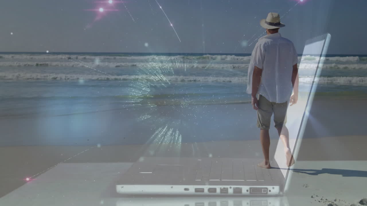Man walking on beach with digital network animation over laptop