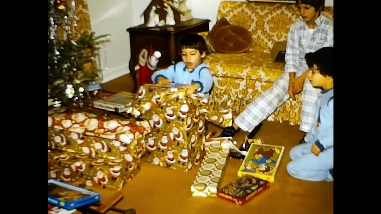 Group of People Surrounding Living Room Filled With Presents. CIRCA USA - 1970s: A group of people from the 1970s in the USA gather around a living room filled with presents.