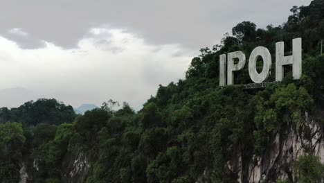 drone fly around limestone mountain with ipoh signage on top of the hill, the capital city of perak, malaysia, southeast asia