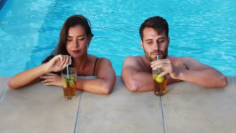 Pareja-Tomando-Té-Helado-Mientras-Interactúa-Junto-A-La-Piscina