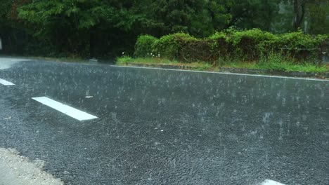 Gotas-De-Agua-Caen-Y-Rebotan-En-El-Asfalto-De-Una-Carretera-Rural-Durante-Una-Fuerte-Lluvia-De-Verano