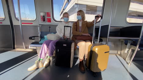 mom and daughter are traveling in a carriage through the airport, their luggage is next to them. protective masks on faces