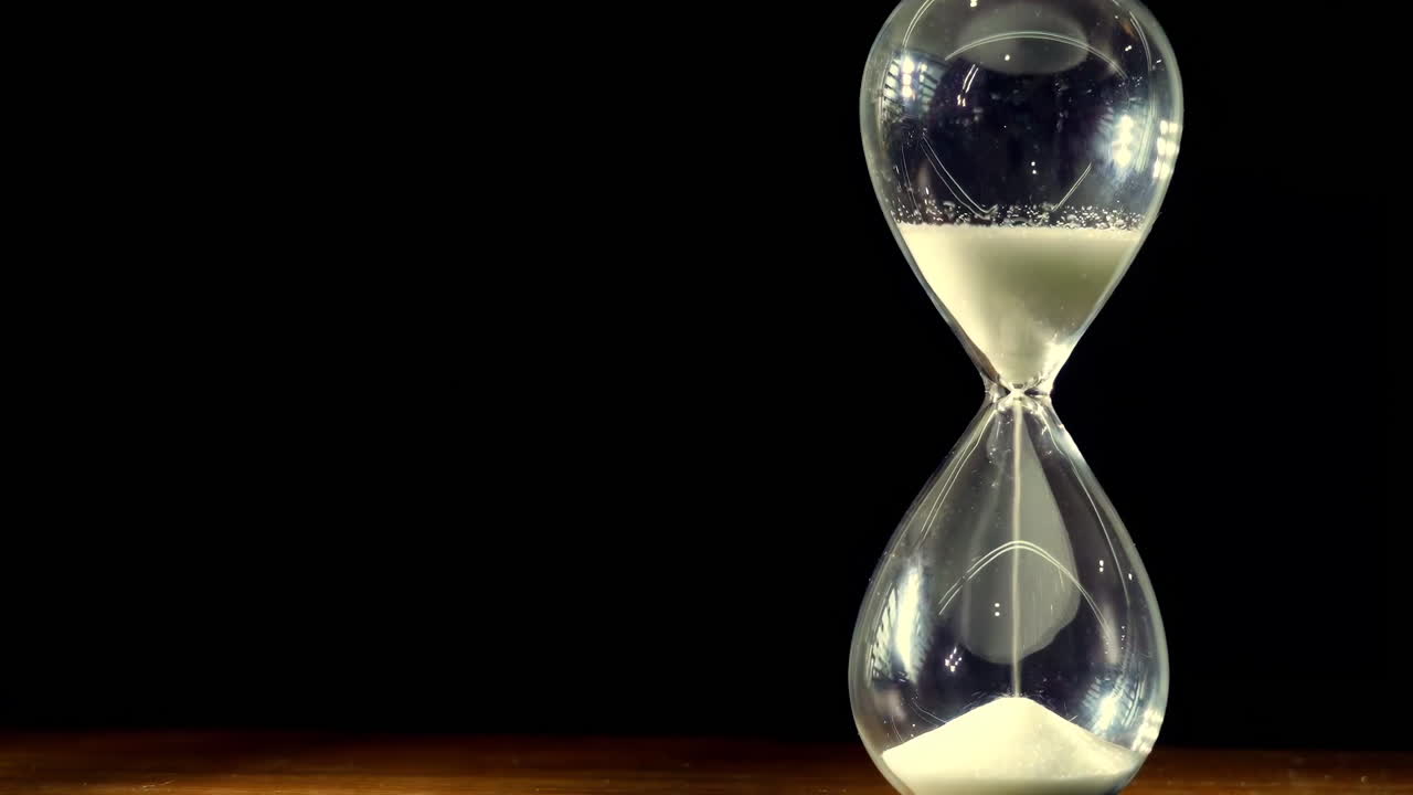 Close up fantasy enchanted hourglass with a glowing silver sand flowing through the bulb of sandglass