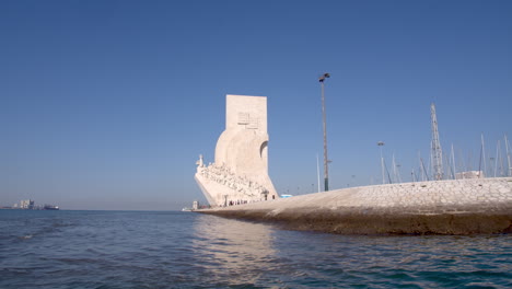 padrão dos descobrimentos monument tracking shot by boat.entering the boat dock and a seagull flying towards the shot.