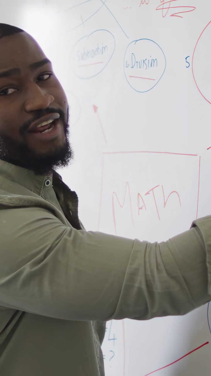 Vertical video: Teacher reaching whiteboard, marking MATH while teaching math with binary overlay