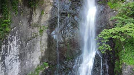 Aerial-view-of-waterfall-surrounded-by-green-planets-and-stones