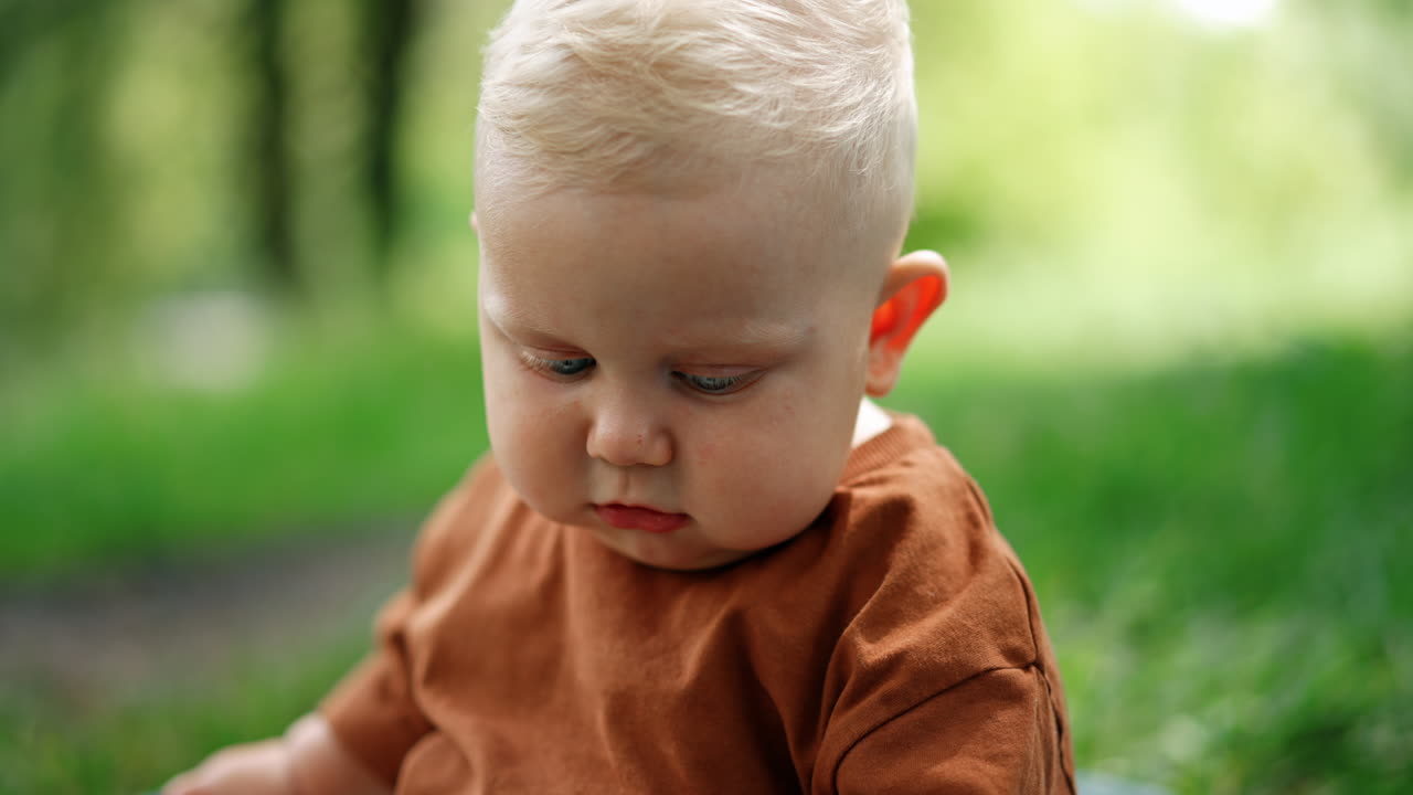 Adorable blond Caucasian baby boy with plump cheeks. Close up portrait of a cute toddler at blurred backdrop.