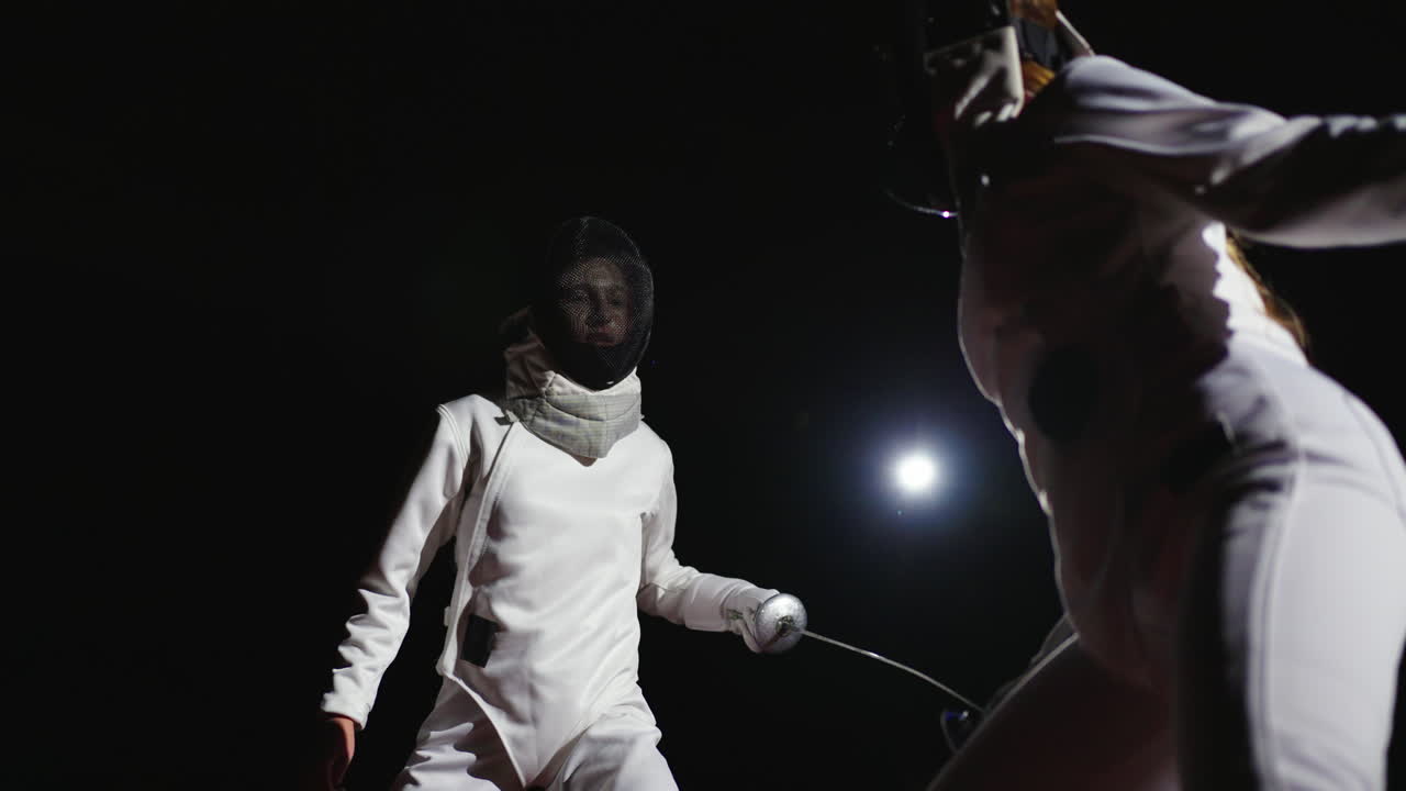 A young woman fencer in action during a competition