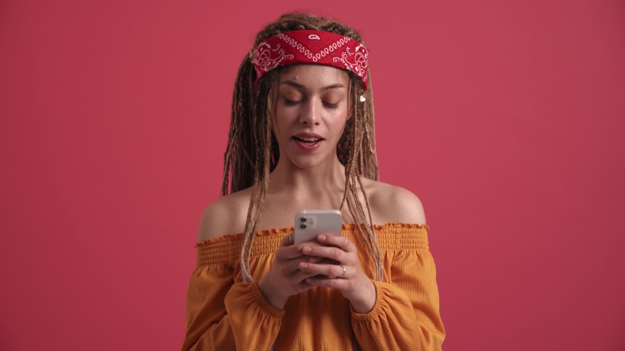 una mujer hippie alegre enviando mensajes de texto por teléfono.