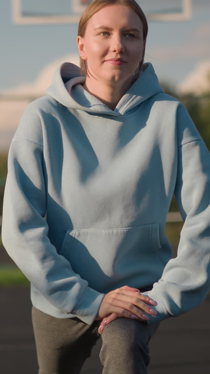 푸른 스웨터를 입은 여자가 야외에서 피트니스 운동을 하며, 밝은 배경과 평온한 분위기 속에서 법정에서 무을 고 스트레칭을 합니다.