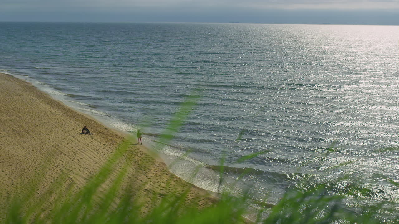 люди наслаждаются морским пейзажем на пляже на открытом воздухе. волны разбиваются на песчаном берегу.