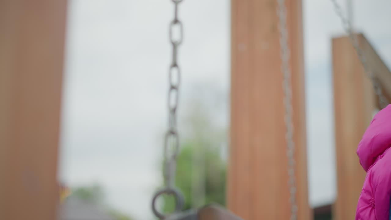 Empty wooden swing on porch, blurred chain and green backyard, overcast sky, shallow focus evokes quiet nostalgia and reflective mood vintage timber post and soft bokeh suggest solitude and calm