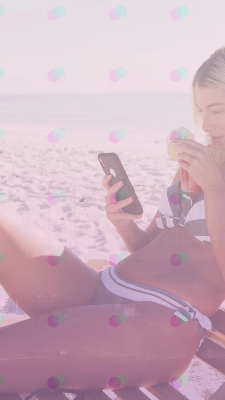 Video verticale: Donna sdraiata in spiaggia dopo aver controllato il telefono, che alza una tazza e sorseggia, scorrendo.