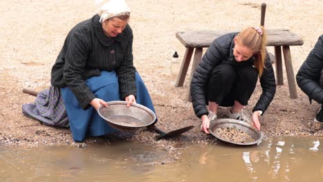 dos mujeres buscando oro en el agua.