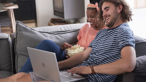 diverse couple, a young african american woman and caucasian man, enjoy a movie at home