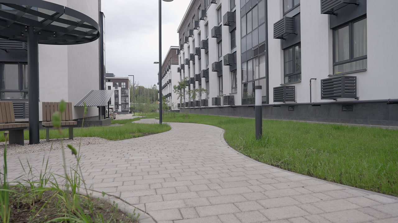 Sweeping Walkway Framed By Apartment Facades, Covered Bench Under Circular Canopy, Lamppost And Manicured