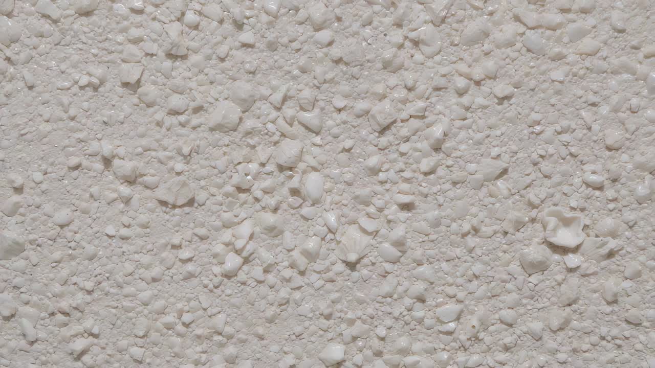 Panoramica della telecamera che rivela da vicino la texture beige in stucco all'interno, mostrando frammenti di ciottoli ed elementi in evidenza
