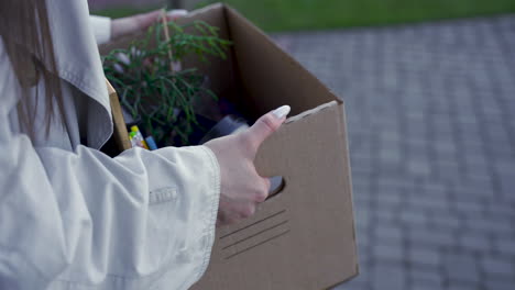 close up of woman's hands carrying things in a box