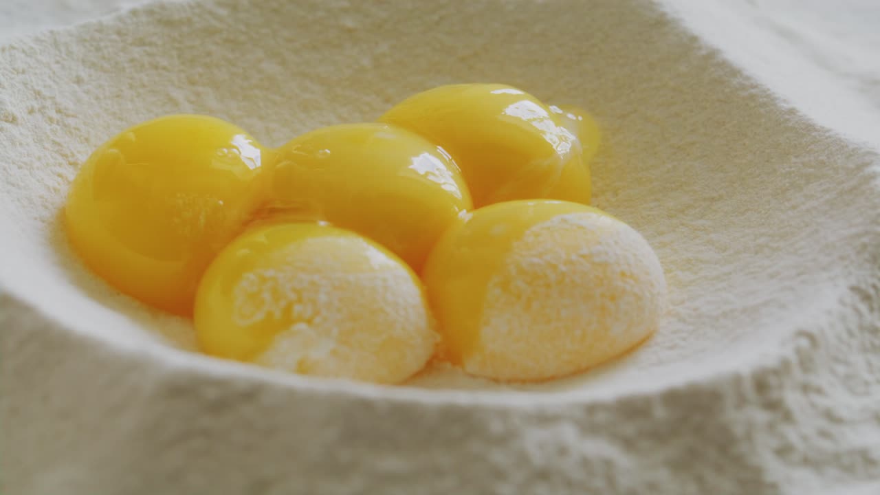 Pouring Egg Yolks into Well in Flour Pile on Kitchen Table
