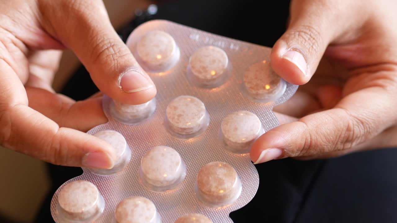 손은 약의 블리스터 패키지를 들고 있습니다.