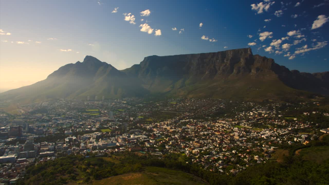 Ripresa drone in 4K sopra gli alberi che rivela la Table Mountain a Città del Capo, Sudafrica, durante la luce del mattino.