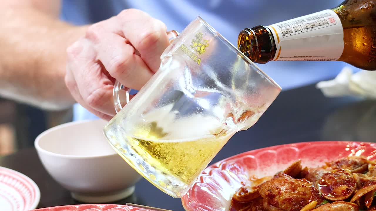 primer plano de la cerveza que se vierte en el vaso en la mesa de comedor