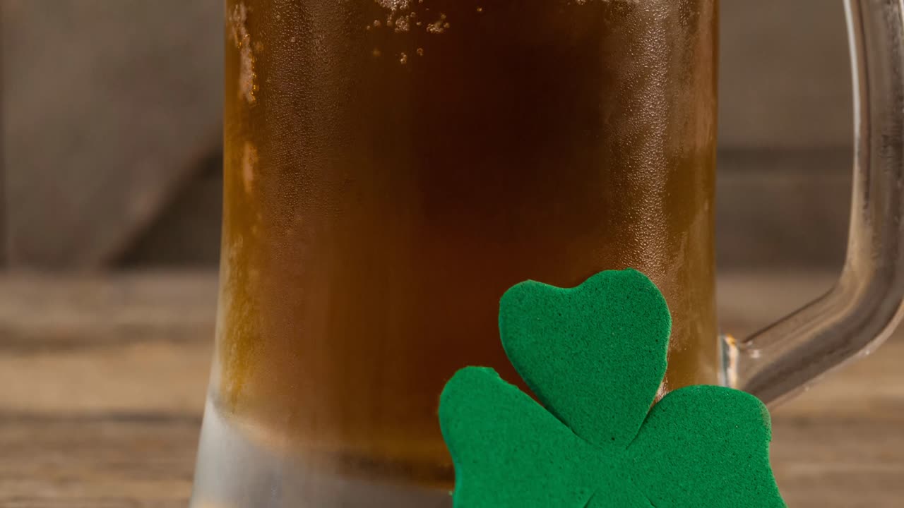 animación de una hoja de trébol apoyada en un vaso de cerveza en el fondo