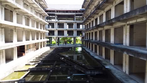 aerial tracking shot of couple exploring an abandoned and overrun hotel resort in bali