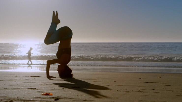 Donna in forma che pratica yoga in spiaggia 4k
