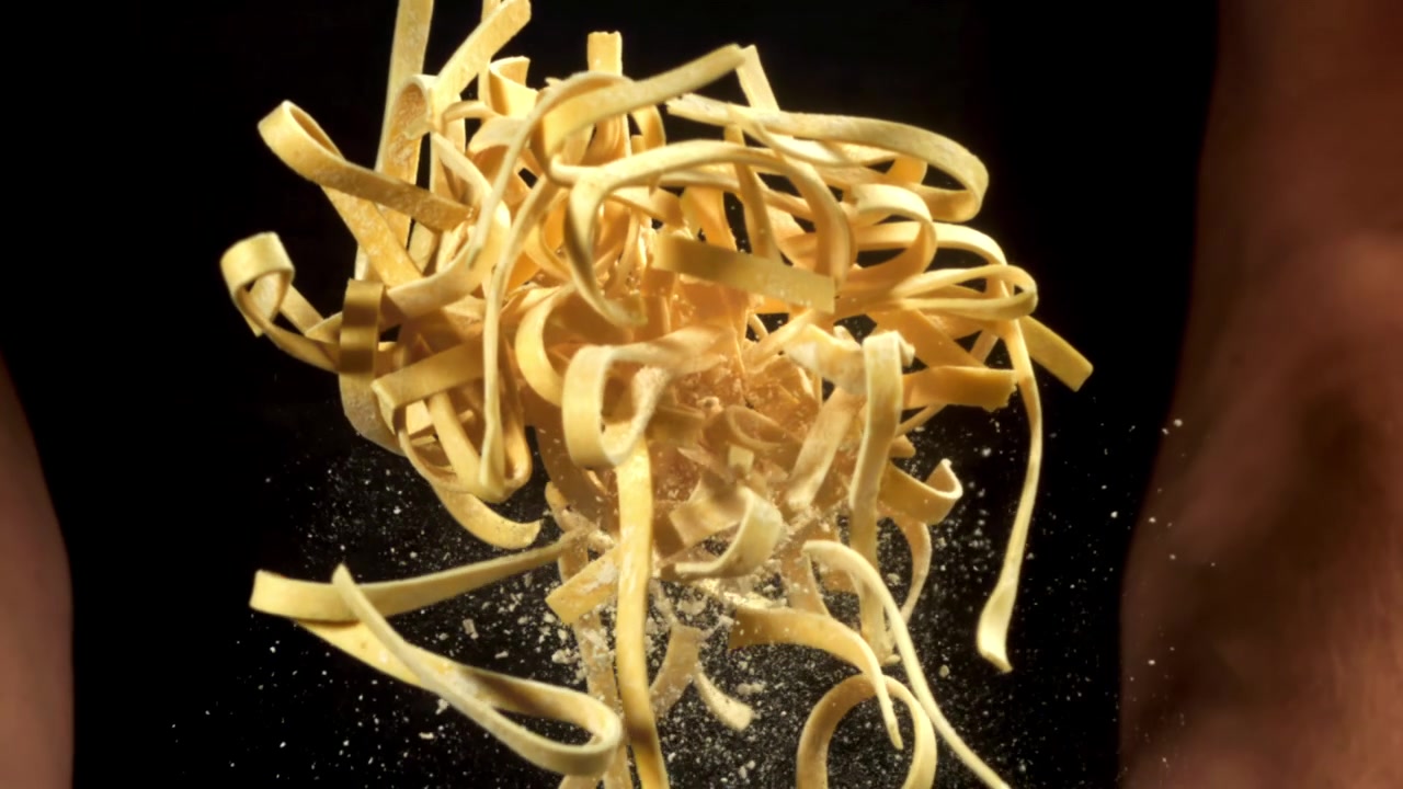Al Rallentatore di Tagliatelle di Pasta Fresca che Vengono Mescolate con la Farina