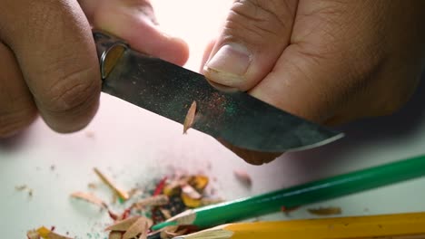 Footage-of-hands-slowly-sharpening-a-pencil-and-some-coloured-pencils-with-a-sharp-knife