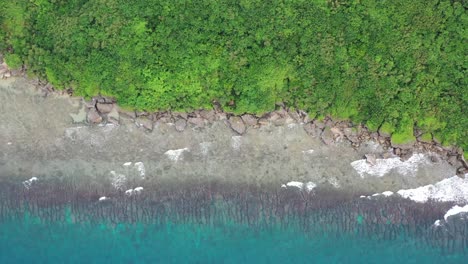 aerial straight down view capturing beautiful turquoise sea water with waves crashing the shore reveals sea god temple at black dwarf cave at xiaoliuqiu lambai island, taiwan