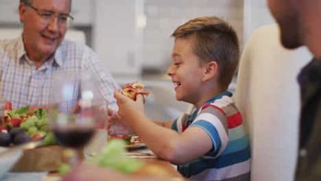 Glücklicher-Kaukasischer-Großvater,-Der-Seinem-Enkel-Beim-Familienessen-Beim-Essen-Am-Tisch-Zuschaut