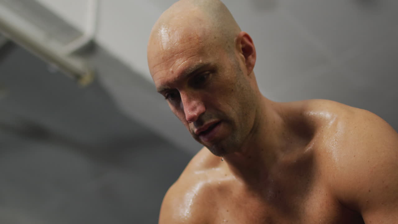hombre caucásico en forma cansado tomando un descanso del entrenamiento en el gimnasio