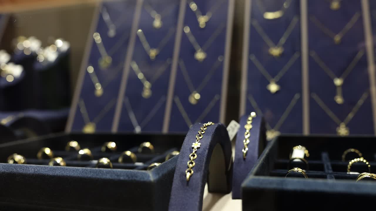 A close-up view of various gold jewelry items, including rings and necklaces, displayed in a store