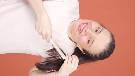 Vertical-video-of-Woman-combing-her-hair.