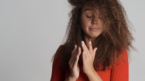 caucasian curly haired woman sneezing in front of the camera.