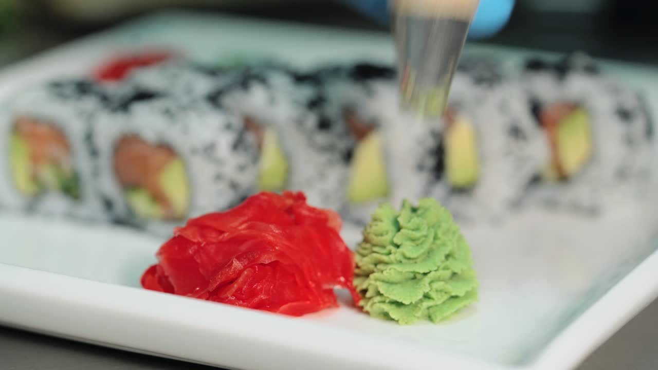 Professional sushi-chef prepares rolls for the client in a commercial kitchen. Serving sushi in a white plate