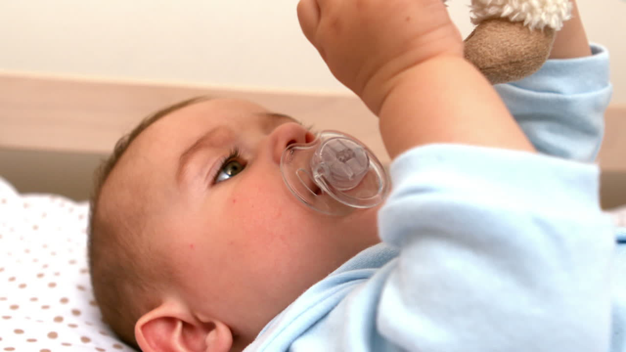 Baby lying in crib sucking soother