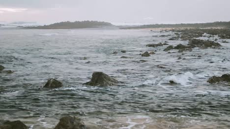 Ondas-De-Luz-Rompiendo-A-Lo-Largo-De-La-Costa-Rocosa-Junto-Al-Mar