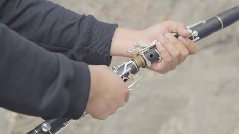 close up of a man's hands attaching a clarinet together