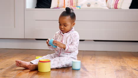 female toddler at home playing with stacking plastic toy