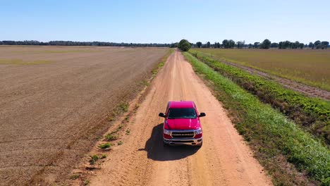 toma aérea de una camioneta roja que viaja por un camino de tierra en una zona agrícola rural de mississippi 6