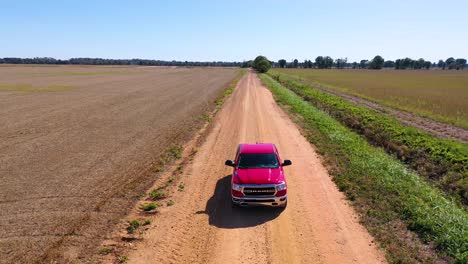 aerial shot of a red pickup truck traveling on a dirt road in a rural farm area of mississippi 6